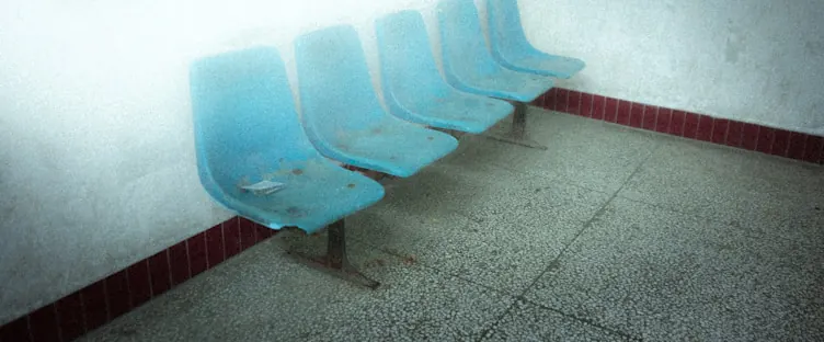 A row of empty seats along a waiting-room wall